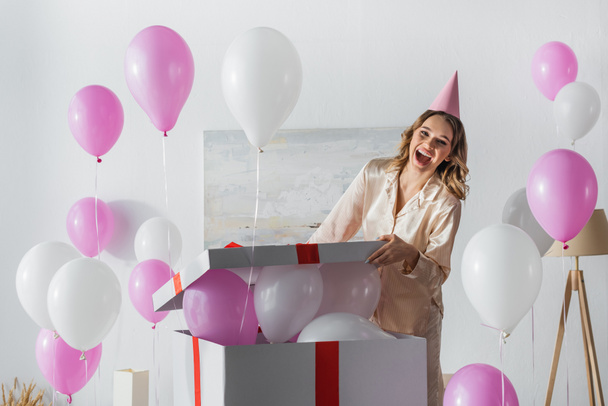Emozionata donna in festa tappo regalo di apertura con palloncini a casa  - Foto, immagini