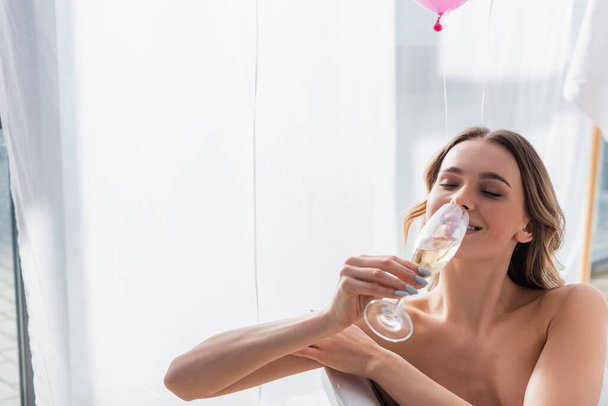 Smiling woman drinking champagne in bathtub  - Photo, Image