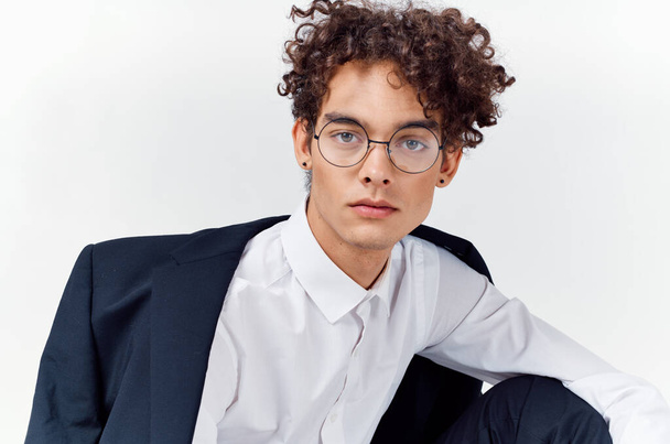 portrait of a curly-haired guy in a shirt in a jacket and glasses on a light background close-up - Fotografie, Obrázek