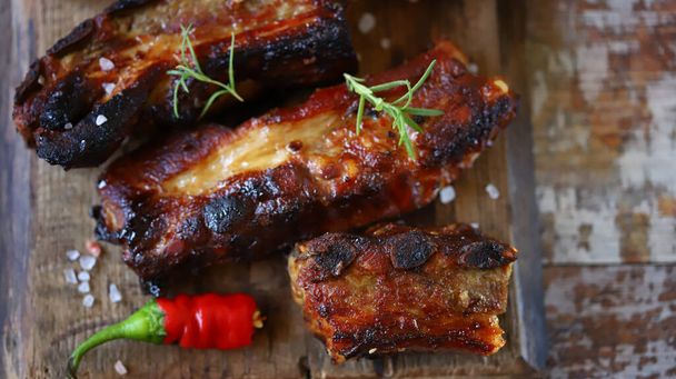 Glazed pork ribs on a wooden board. Cooking BBQ ribs. - Photo, Image