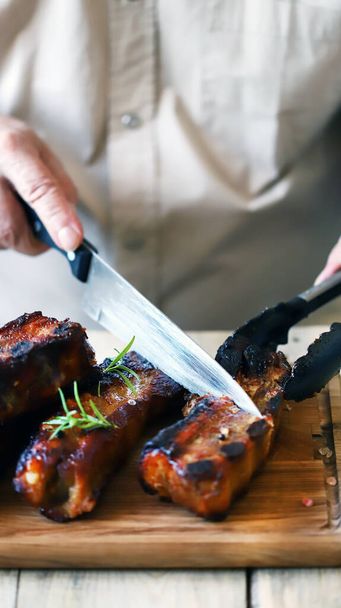 Chef con un coltello taglia costole barbecue sulla tavola. - Foto, immagini