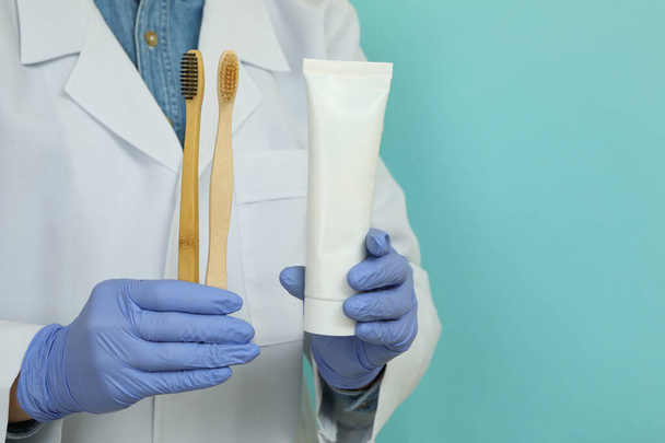 Doctor hold toothpaste and toothbrushes on blue background - Photo, Image
