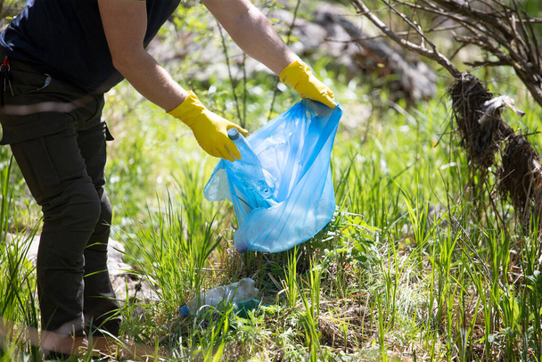 Hand picking up garbage plastic for cleaning the woods or parks. Environmental protection, Earth Day, volunteer concept. - Foto, afbeelding