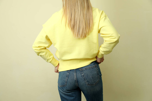 Młoda kobieta w żółtej bluzie na beżowym tle - Zdjęcie, obraz