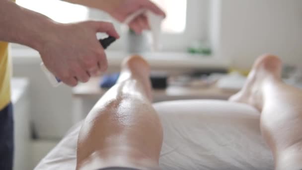 De masseur behandelt de atleten been met alcohol en veegt met een handdoek  - Video