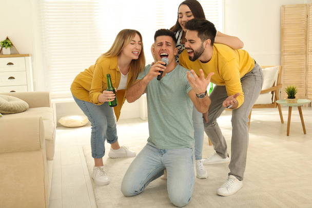Happy friends singing karaoke together at home - Foto, afbeelding