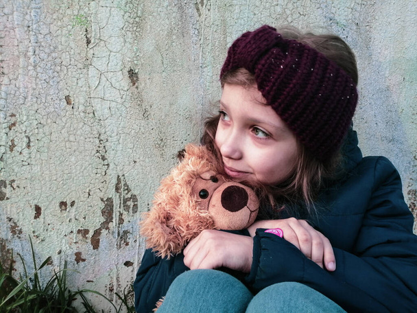 Eski grunge duvar arka planında favori oyuncak ayısı olan küçük bir genç kız. - Fotoğraf, Görsel