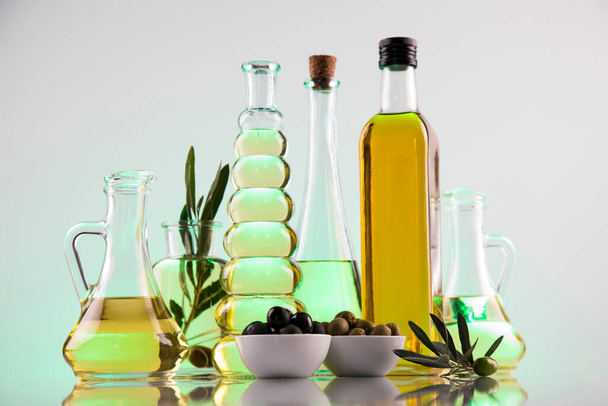 Butelki oliwy z oliwek, gałąź oliwna i oleje do gotowania - Zdjęcie, obraz