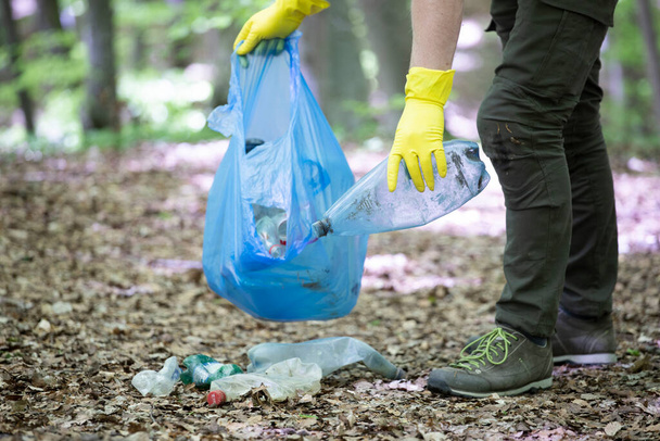Hand picking up garbage plastic for cleaning the woods or parks. Environmental protection, Earth Day, volunteer concept. - Fotografie, Obrázek
