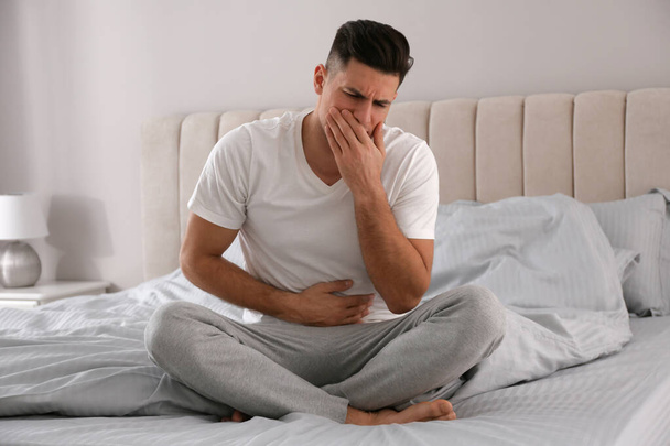Man suffering from nausea on bed at home. Food poisoning - Фото, изображение