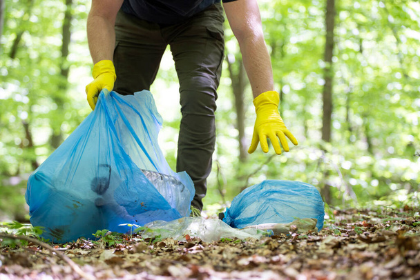 Hand picking up garbage plastic for cleaning the woods or parks. Environmental protection, Earth Day, volunteer concept. - Foto, afbeelding