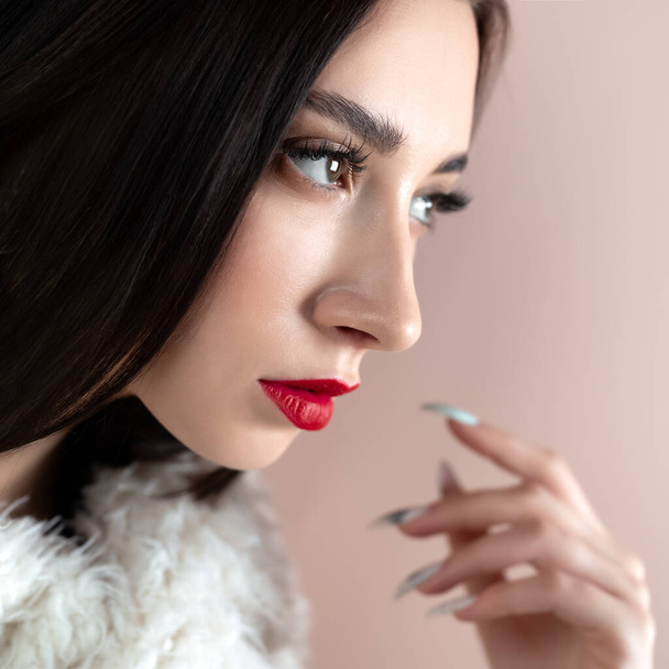 Young woman with great shapes brows, long eyelashes and red lips. Brunette posing on white wall. - Foto, imagen