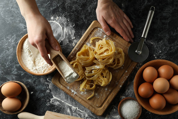 Woman cooking tasty pasta on dark table - Photo, Image