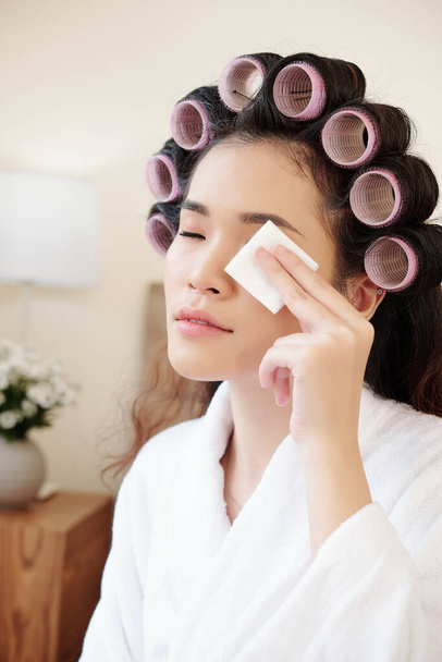 Beautiful young woman removing eye make-up with cotton pad with miccelar water - Photo, Image