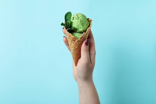 Naisten käsi pidä minttu jäätelöä sinisellä pohjalla - Valokuva, kuva