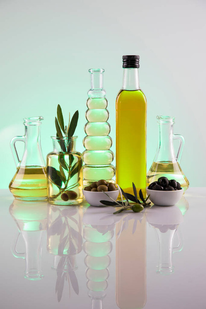 Bottles with organic cooking olive oil and olive branch - 写真・画像