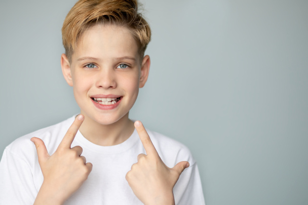 Хлопець посміхається і показує зуби руками. Стоматологічна медицина та охорона здоров'я
 - Фото, зображення