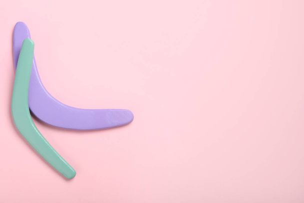 Boomerangs de madera de colores sobre fondo rosa, disposición plana. Espacio para texto - Foto, imagen