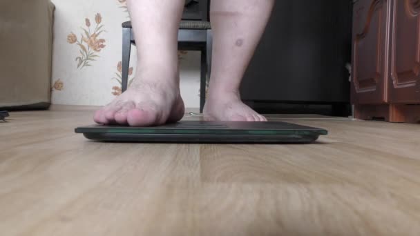 een persoon stapt op een weegschaal om zijn gewicht te achterhalen - Video