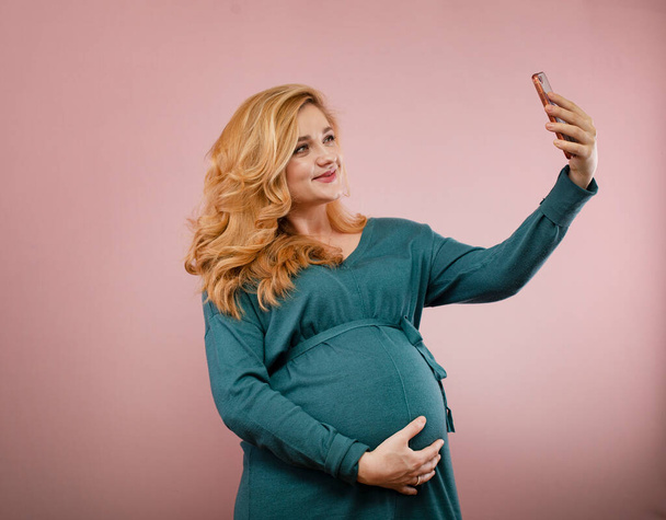 young pregnant woman is talking by video call on smartphone - Foto, afbeelding