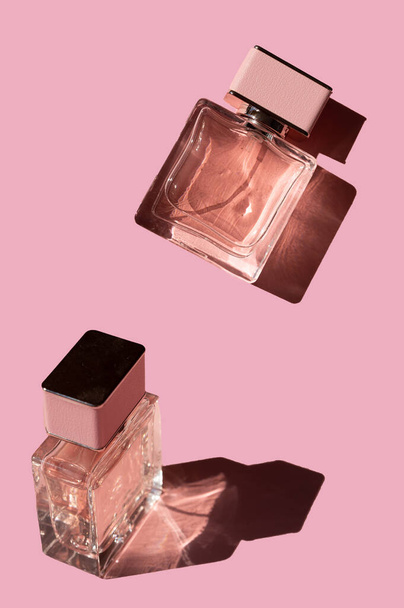 Perfumy Fragnance. Butelki perfum różowej kobiety na pastelowym różowym tle,. Makijaż perfum zapachowych. Modna koncepcja minimalnego światła słonecznego - Zdjęcie, obraz