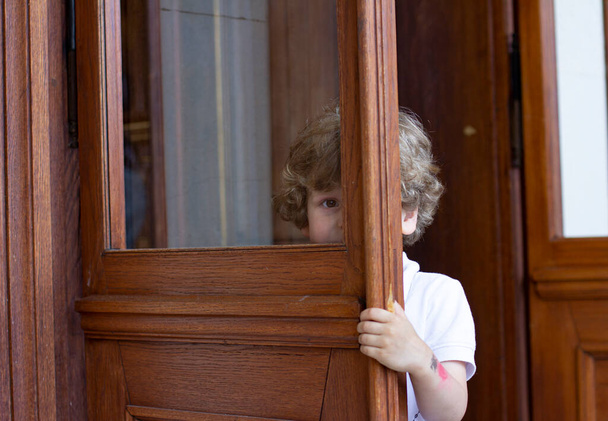 Le petit garçon se cache derrière la porte - Photo, image
