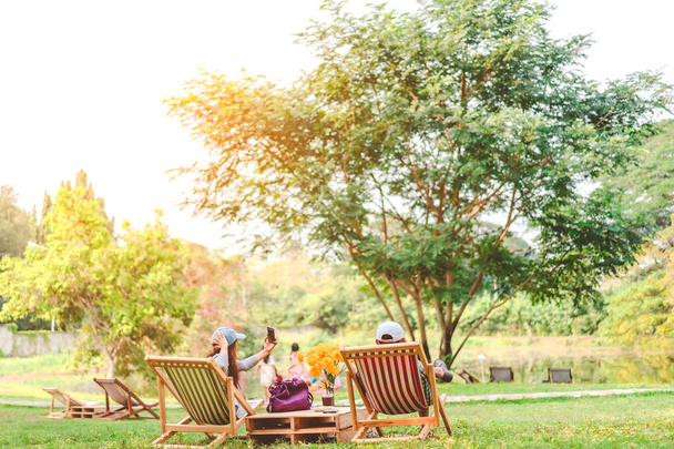 Щастя пара в літній відпустці сидить на садових стільцях, щоб розслабитися в громадському парку
. - Фото, зображення