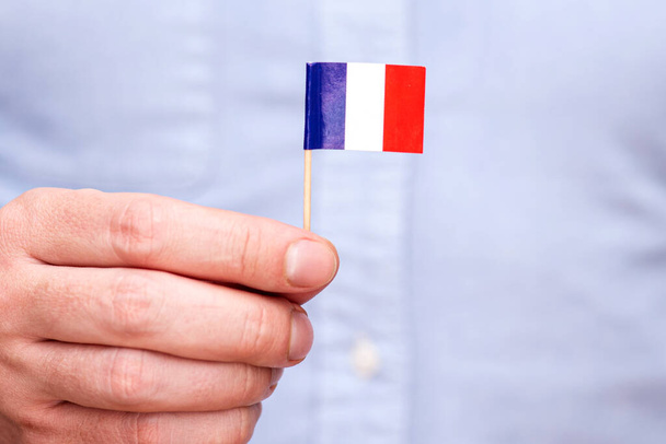 A man holding paper flag of France on wooden toothpick , concept picture - 写真・画像