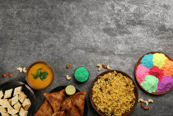Traditional Indian food and color powders on grey table, flat lay with space for text. Holi festival celebration - Foto, Imagen
