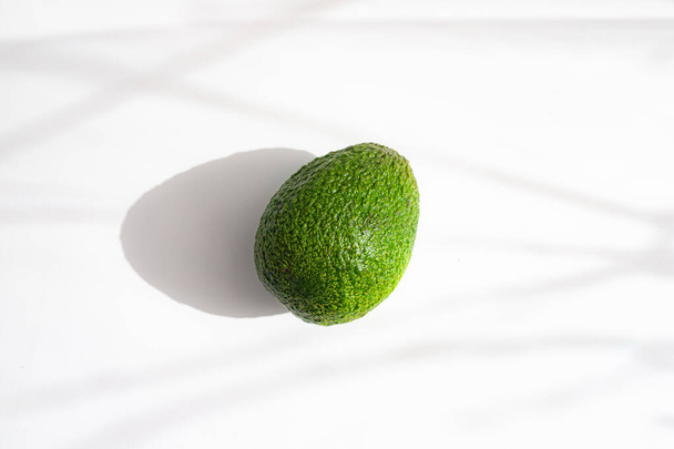 Avocado on a white background with shadows . Proper nutrition. Keto diet. Article about the benefits and harms of avocado. Avocado copy space - Foto, Bild