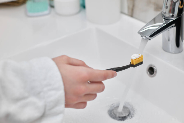 female hand holding toothbrush with paste in bathroom - Photo, Image