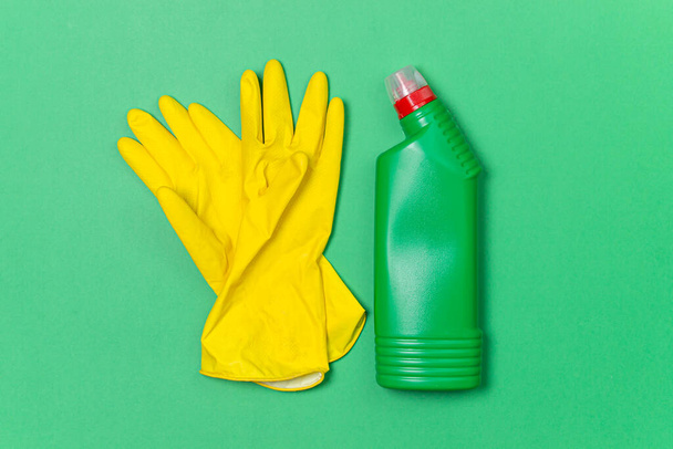 Cleaning products on a colored background. Indoor cleaning tools. Rubber gloves and detergent on green background - Φωτογραφία, εικόνα