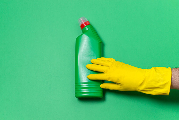 Καθαρισμός προϊόντων σε έγχρωμο φόντο. Εργαλεία καθαρισμού εσωτερικών χώρων. Ελαστικά γάντια και απορρυπαντικό σε πράσινο φόντο - Φωτογραφία, εικόνα