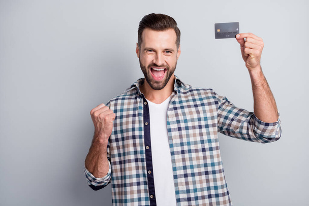 Photo portrait of cheerful man showing bank card gesturing like lottery winner isolated on grey color background - Foto, Imagen