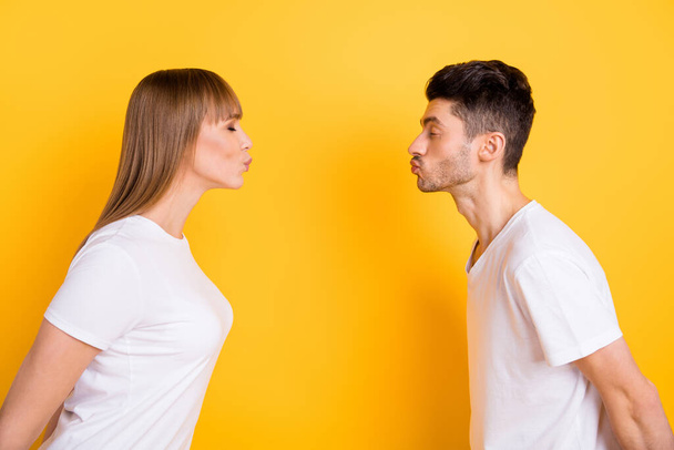 Photo of adorable dreamy young couple wear white t-shirt ready kissing each other closed eyes isolated yellow color background - Fotografie, Obrázek