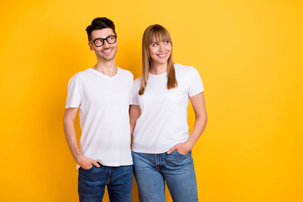 Photo of charming sweet young couple wear white t-shirt spectacles hugging looking empty space isolated yellow color background - Foto, immagini