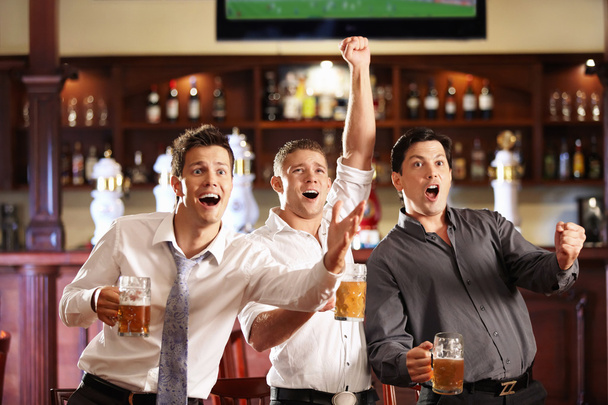 Young met bier voetbal in een bar kijken - Foto, afbeelding
