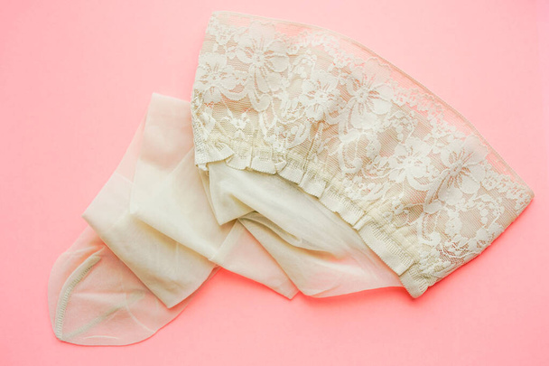 New creamy stockings with elastic lace on the pale pink table. - Zdjęcie, obraz