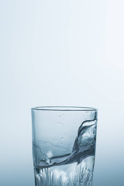 Splash, salpicando água em um copo em um fundo branco. - Foto, Imagem