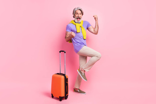 Photo of aged man happy rejoice win victory baggage trip vacation air fly tied sweater isolated over pink color background - Фото, изображение