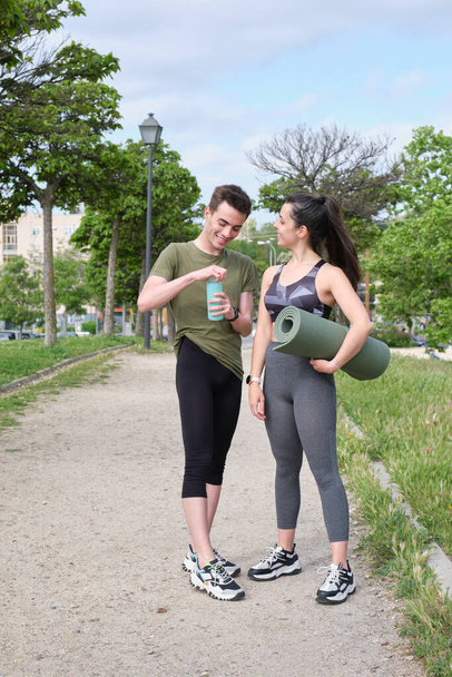 Giovane coppia sportiva che ride in piedi in un parco. Concetto fitness. - Foto, immagini