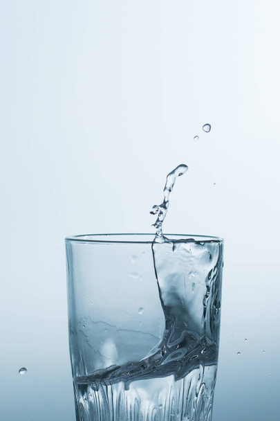 Woda lub napój alkoholowy w szklance, chlapanie, zbliżenie. - Zdjęcie, obraz