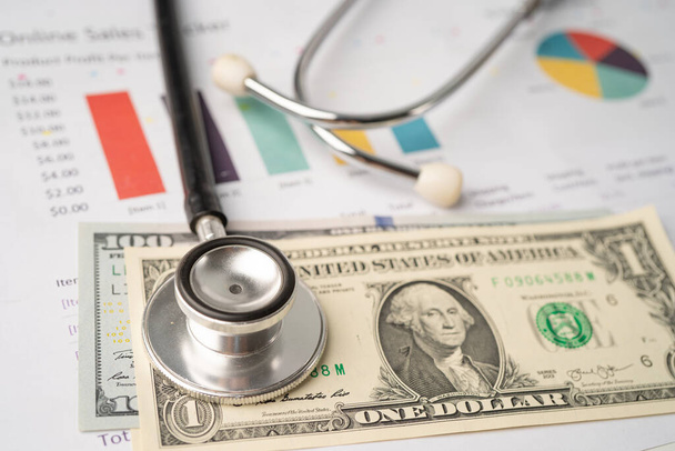Stethoscope and US dollar banknotes on chart or graph paper, Financial, account, statistics and business data  medical health concept. - Photo, Image