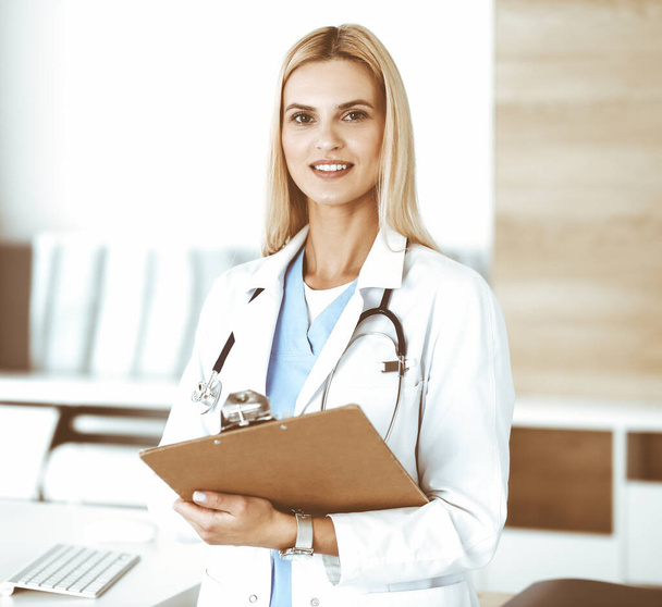 Doctor woman at work in hospital controls medication history records and exam results while using clipboard. Medicine and healthcare concept - Foto, Imagen