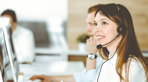 Group of diverse operators at work in call center. Beautiful asian woman sitting in headset at customer service office. Business concept - 写真・画像