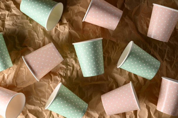De arriba de las copas de papel de color arregladas sobre papel artesanal arrugado. Concepto libre de plástico, vajilla biodegradable, reciclable. Residuos cero - Foto, Imagen