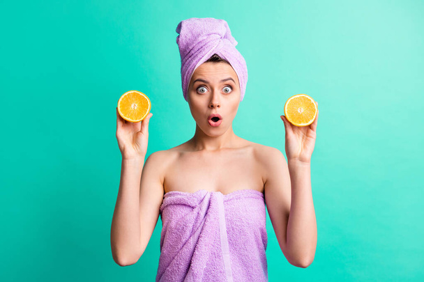 Photo of attractive speechless lady hold orange slices listen useful fruit action wear violet towels isolated teal color background - Фото, зображення
