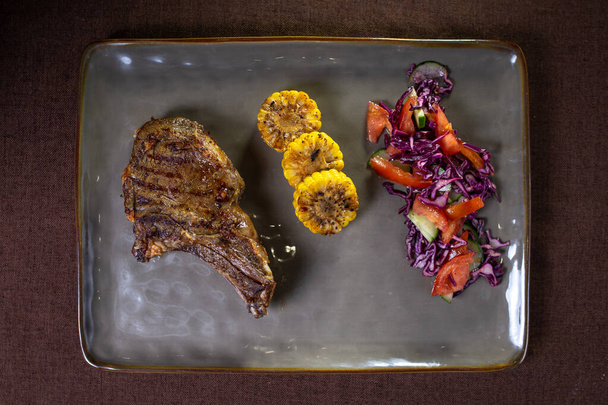Beef steak with corn and salad on a gray plate view from top. - Photo, Image