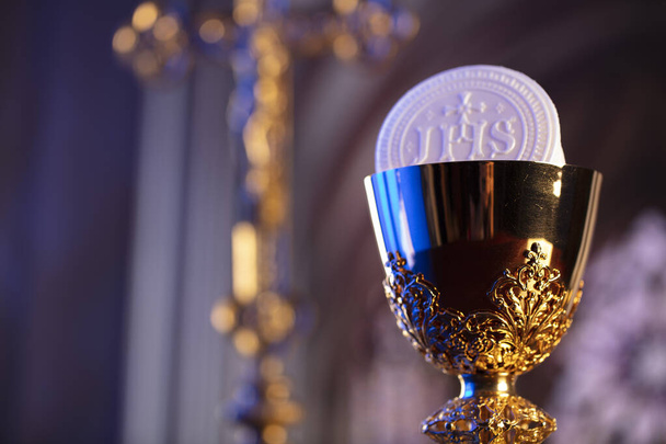 Первое причастие. Тема католической религии. Распятие, хорватская и золотая чаши и вафли на алтаре. - Фото, изображение