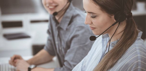 Call center. Group of casual dressed operators at work. Brunette business woman in headset at customer service office - Foto, imagen